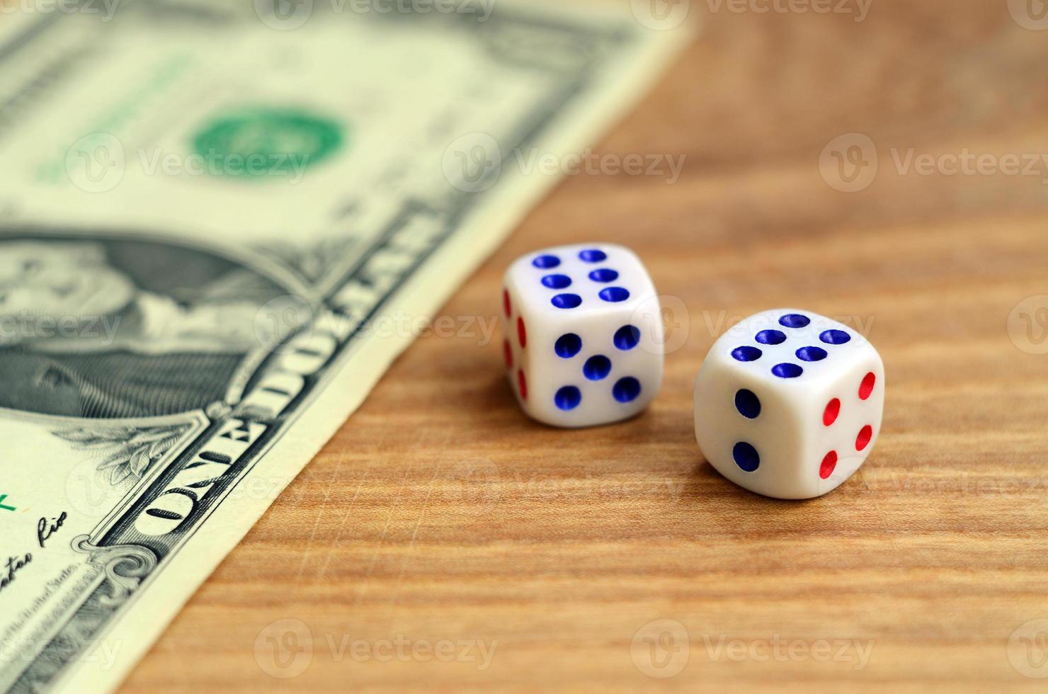 White dice are next to a dollar bill of US dollars on a wooden background. The concept of gambling with rates in monetary units photo