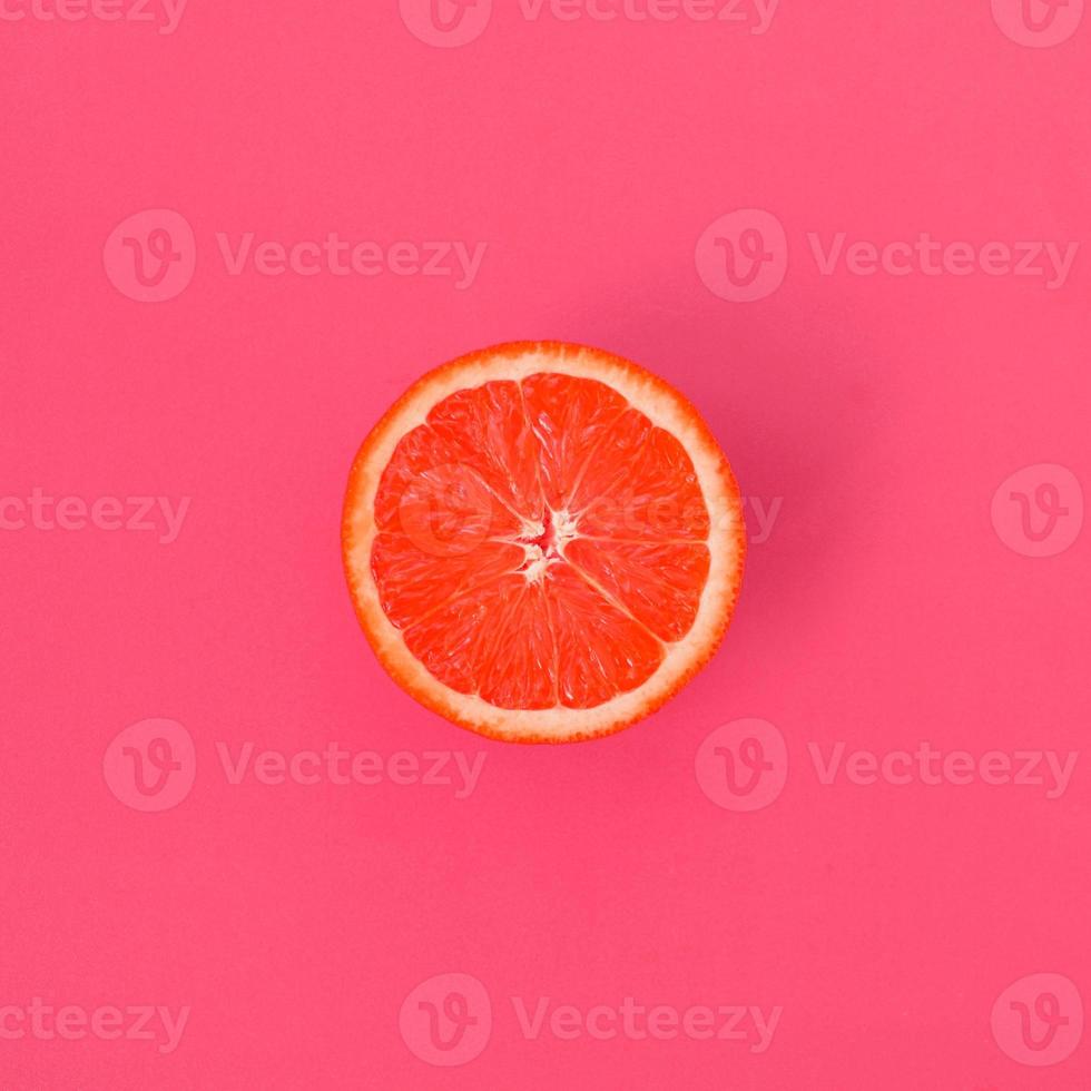 Top view of a one grapefruit slice on bright background in light pink color. A saturated citrus texture image photo