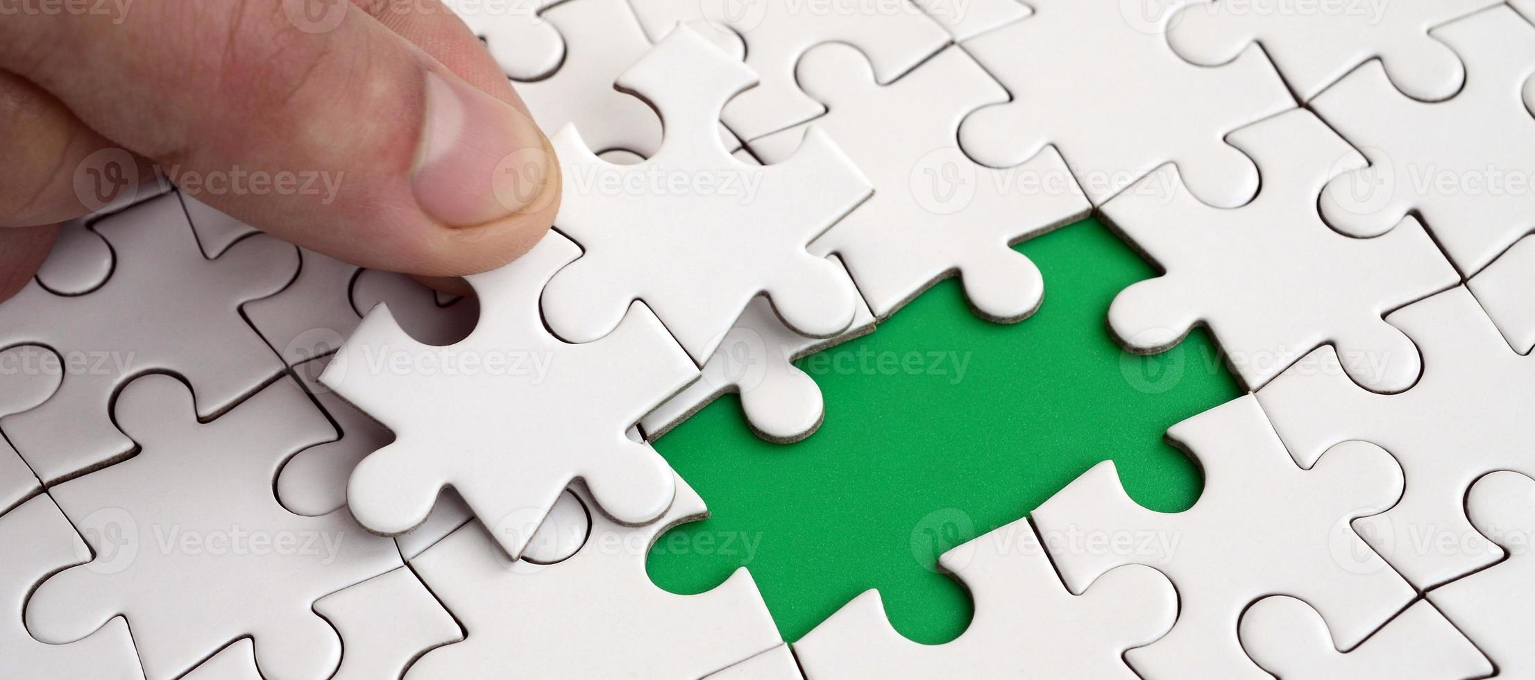 The human hand fills the last missing elements of the surface from the jigsaw puzzle. The concept of the completion of the initiated cases photo