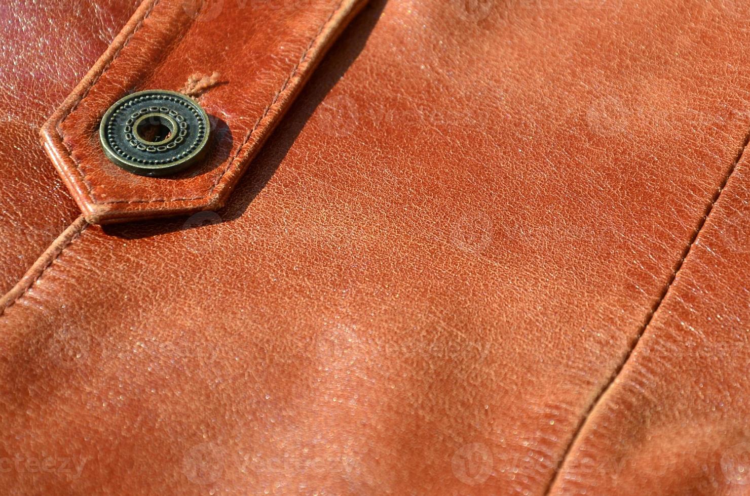 Brown leather texture. Useful as background for any design work. Macro photo of a button on outer clothing made of genuine leather