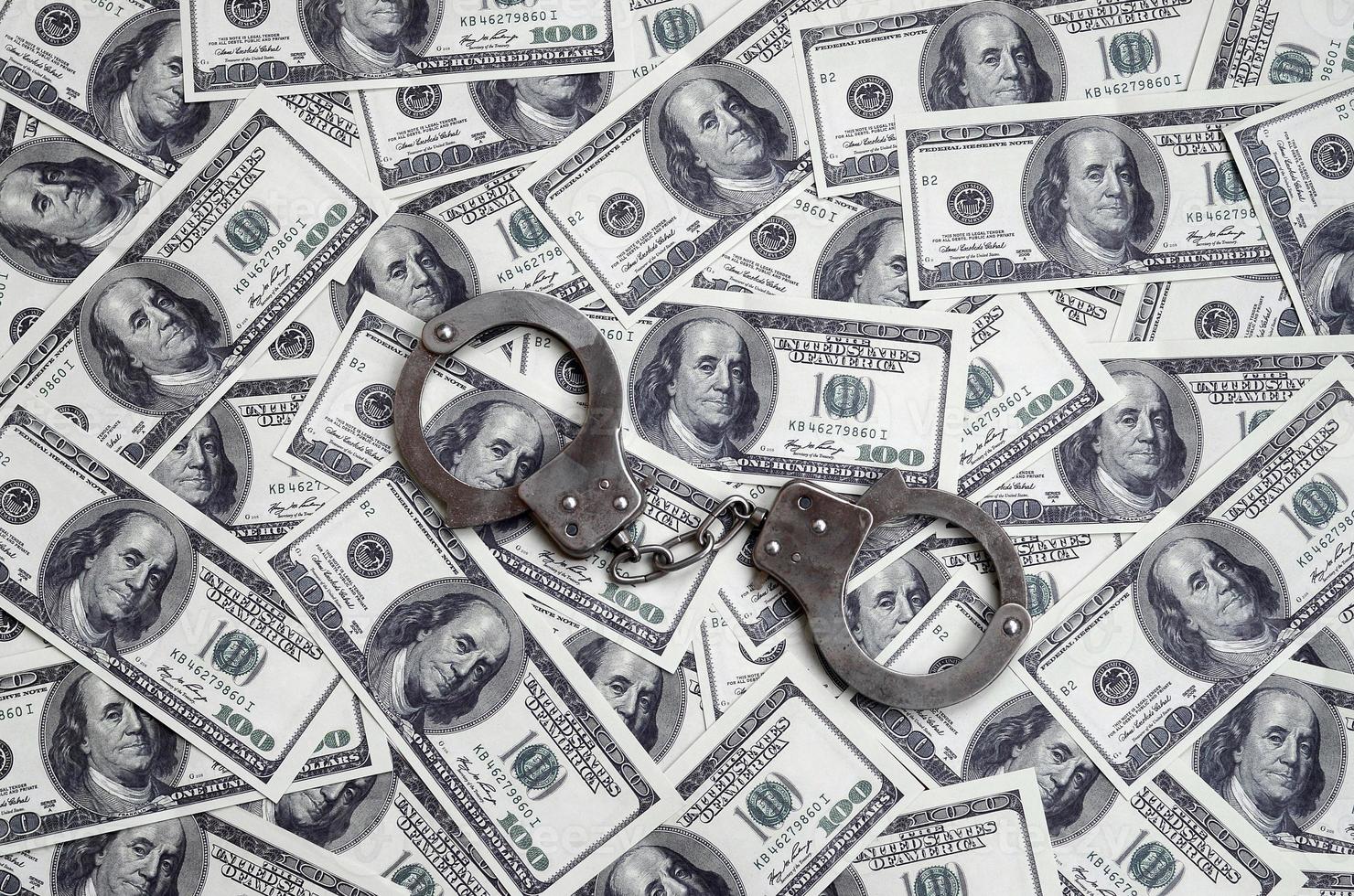 Police handcuffs lie on a lot of dollar bills. The concept of illegal possession of money, illegal transactions with US dollars. Economic Crime photo