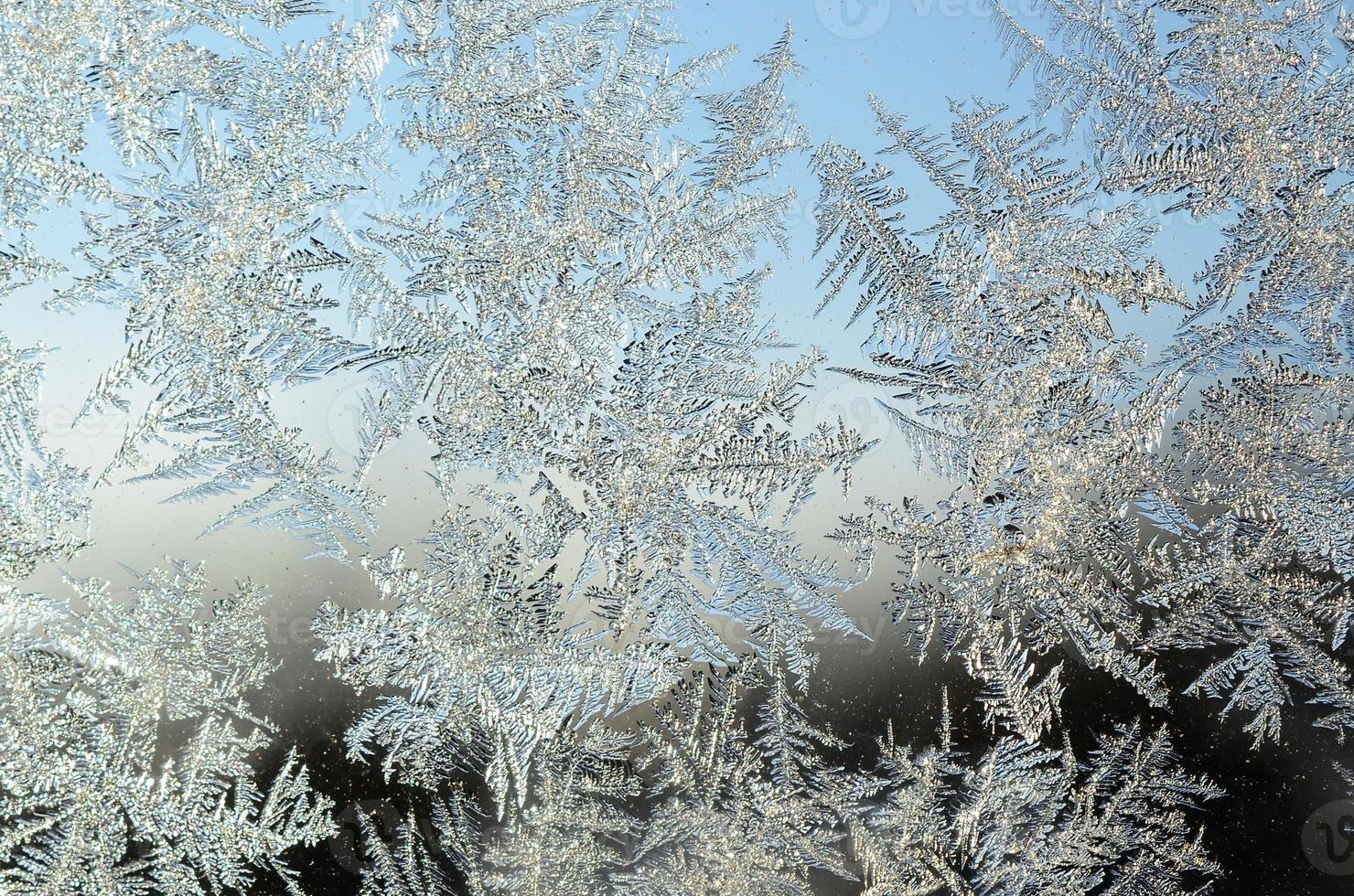 Snowflakes frost rime macro on window glass pane photo