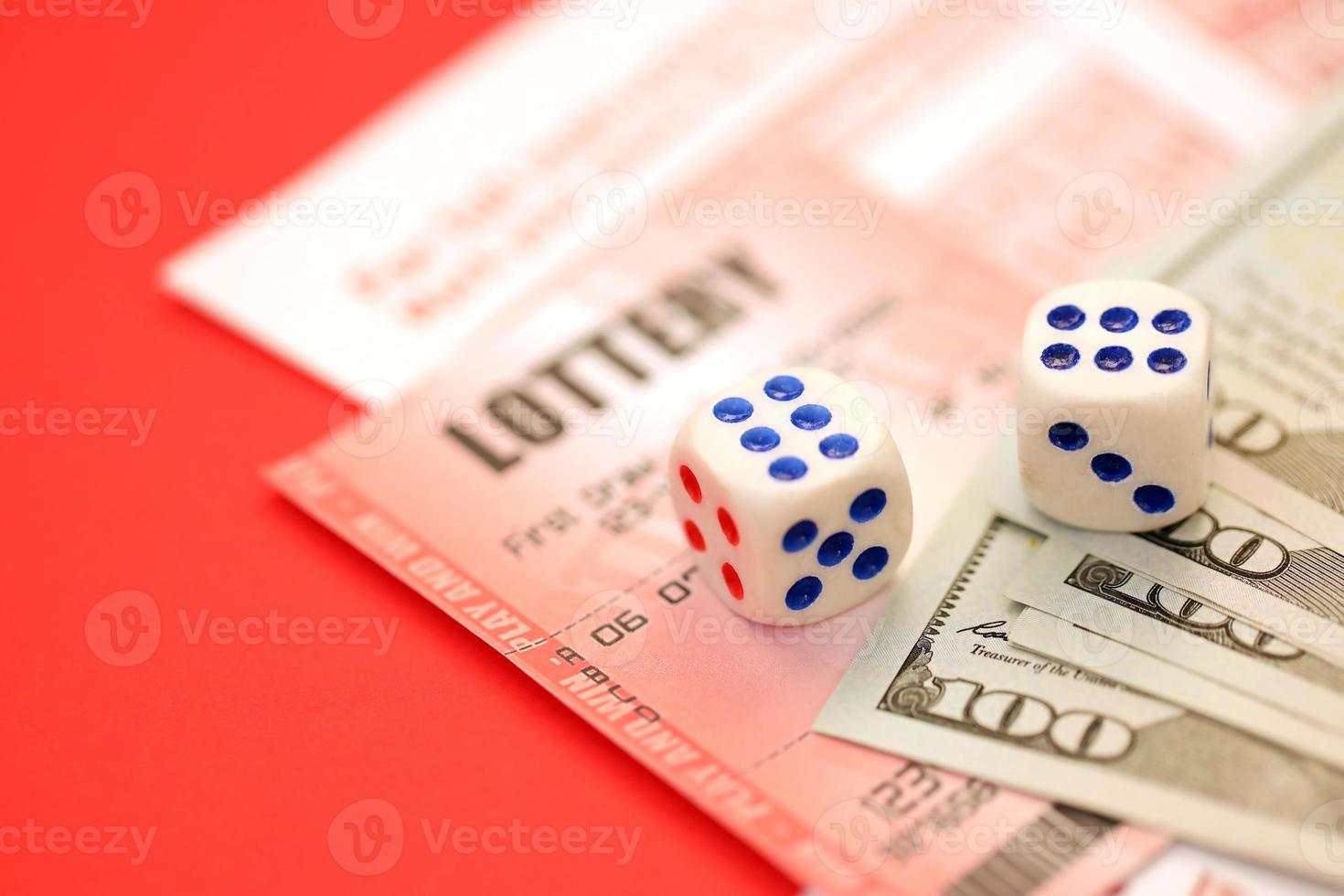 Red lottery ticket with dice and money lies on pink gambling sheets with numbers for marking to play lottery. Lottery playing concept or gambling addiction. Close up photo