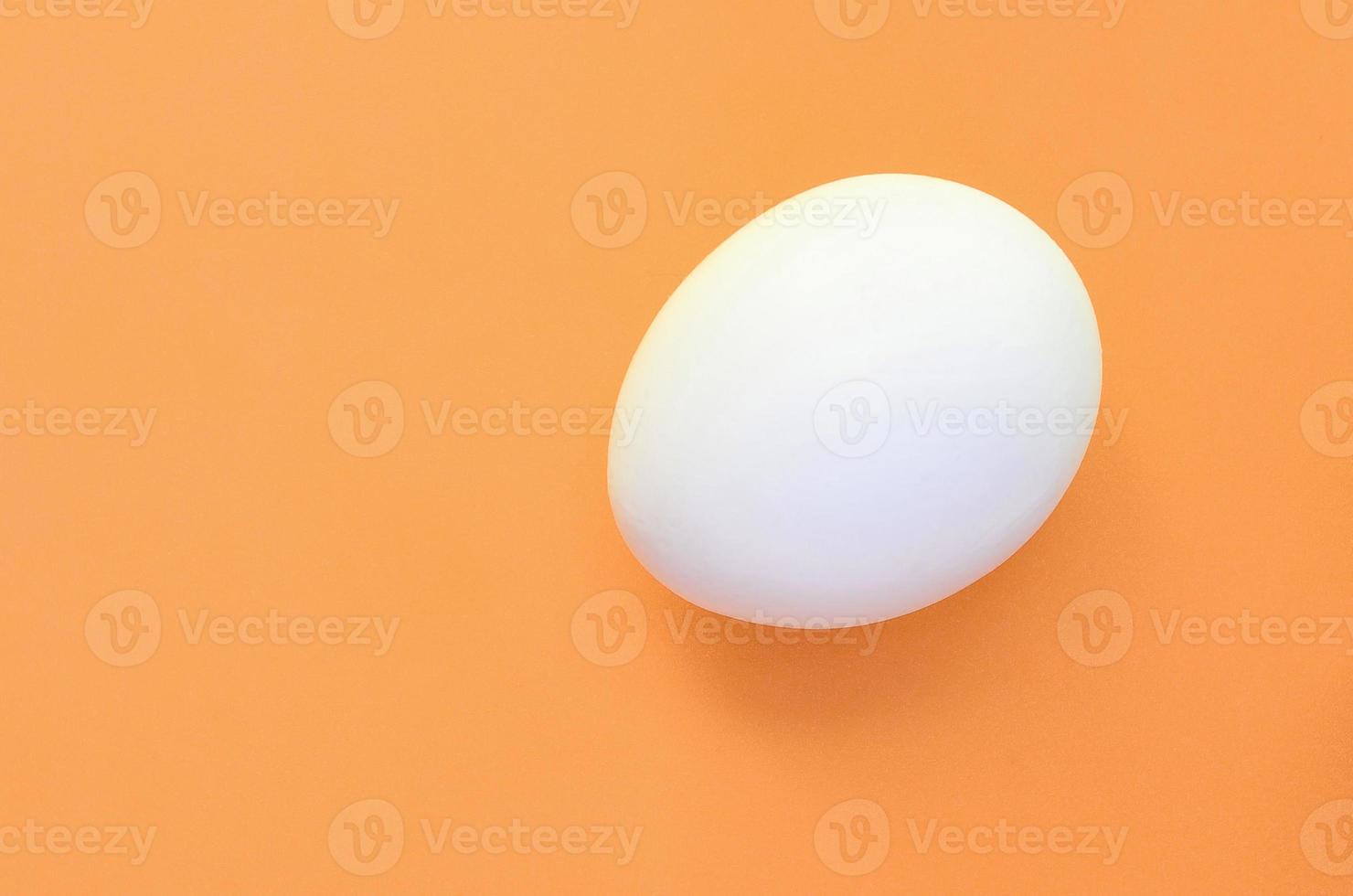 One white easter egg on a bright orange background photo