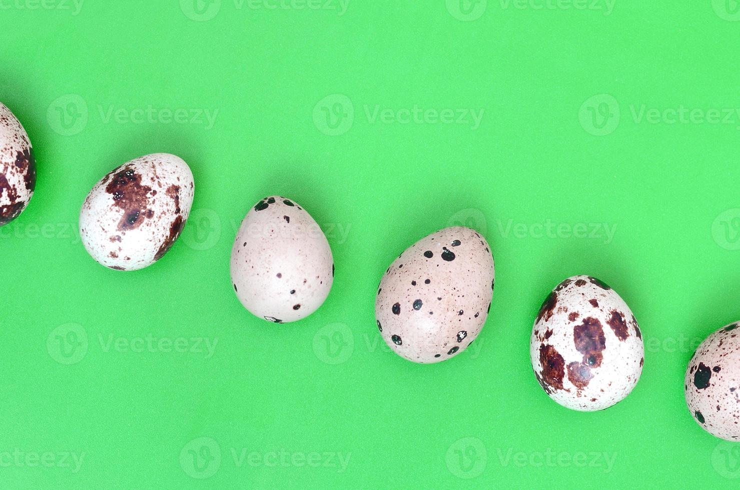 Quail eggs on a light green surface, top view, empty place for t photo
