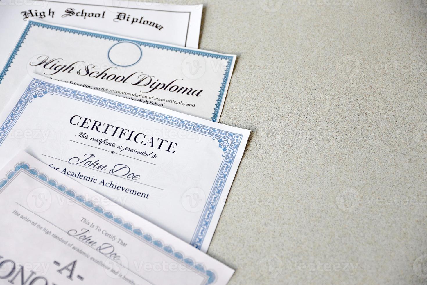 A honor roll recognition, certificate of achievement and high school diploma lies on table. Education documents photo