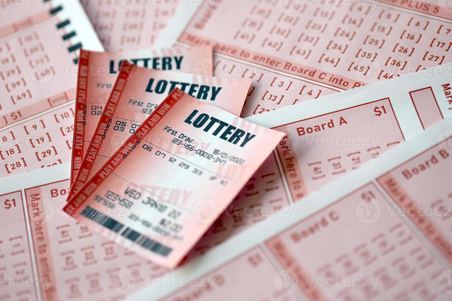 Red lottery ticket lies on pink gambling sheets with numbers for marking to play lottery. Lottery playing concept or gambling addiction. Close up photo