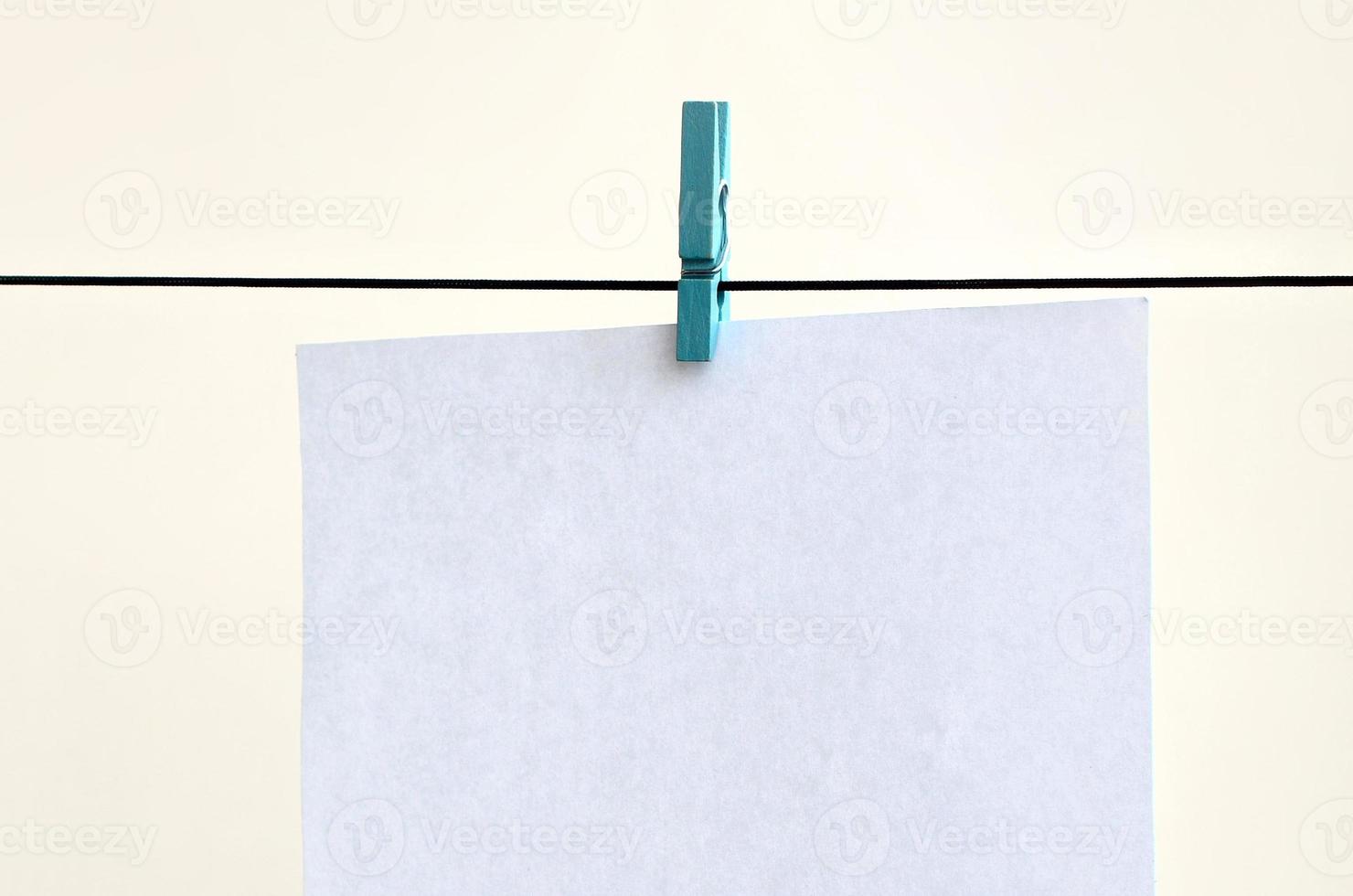 White blank cards on rope, light wall background. Creative reminder, small sheets of paper on old clothespin, memo backdrop photo