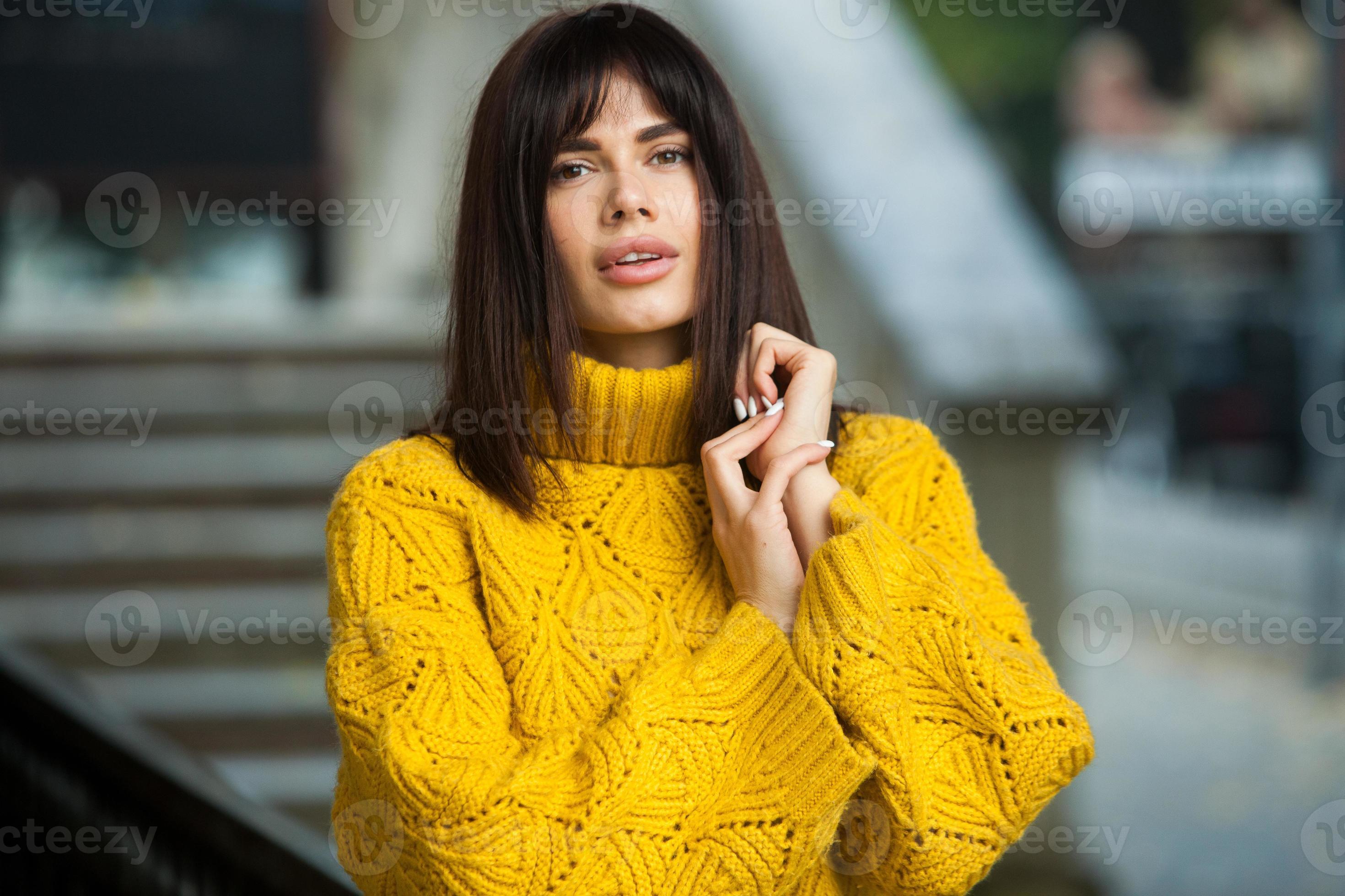 Beautiful European brunette dressed in a yellow woolen sweater and hat  outside. The beautiful girl who wears thick stylish autumn clothes in cool  weather. 12824197 Stock Photo at Vecteezy