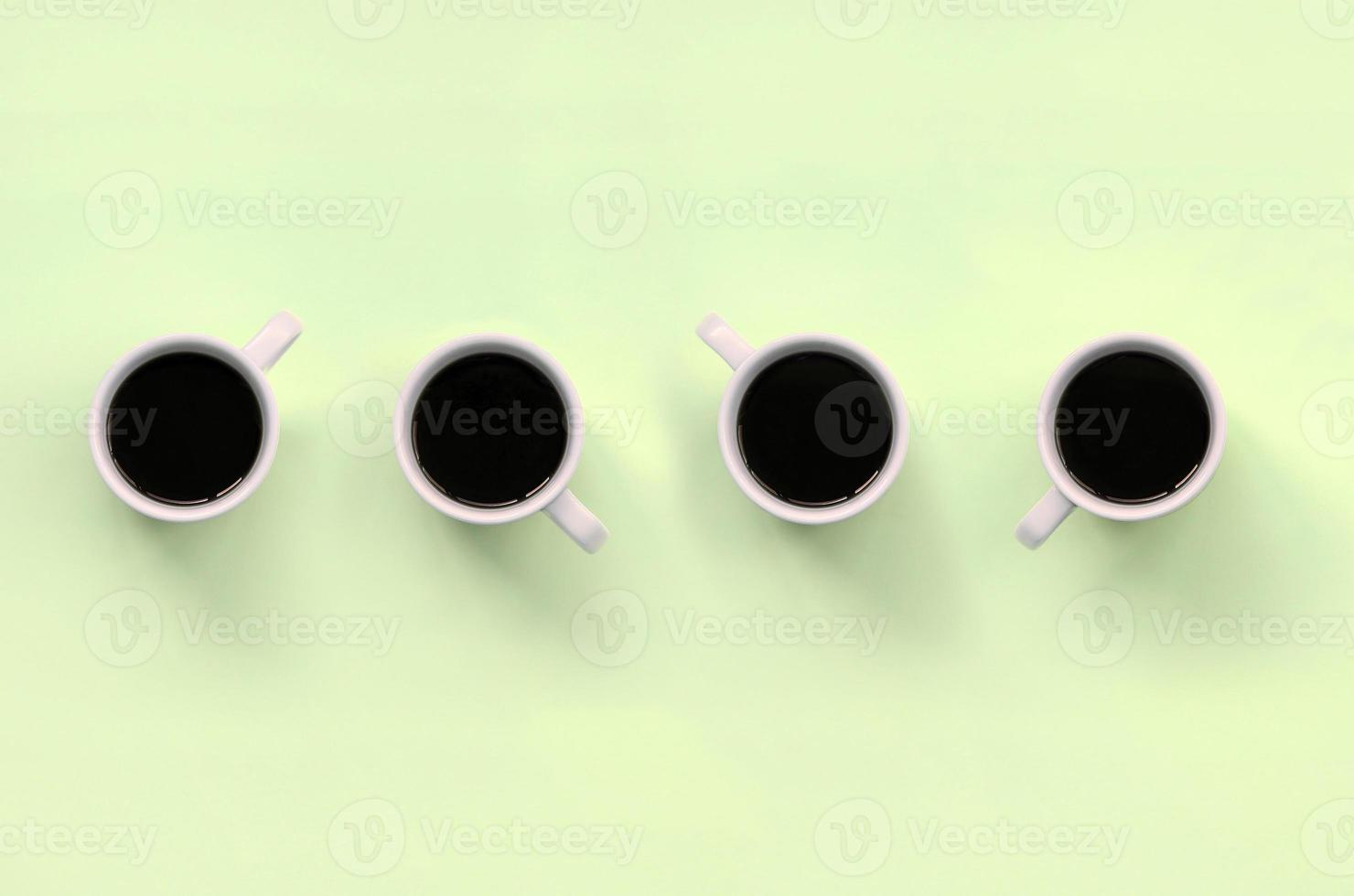 Many small white coffee cups on texture background of fashion pastel lime color paper photo