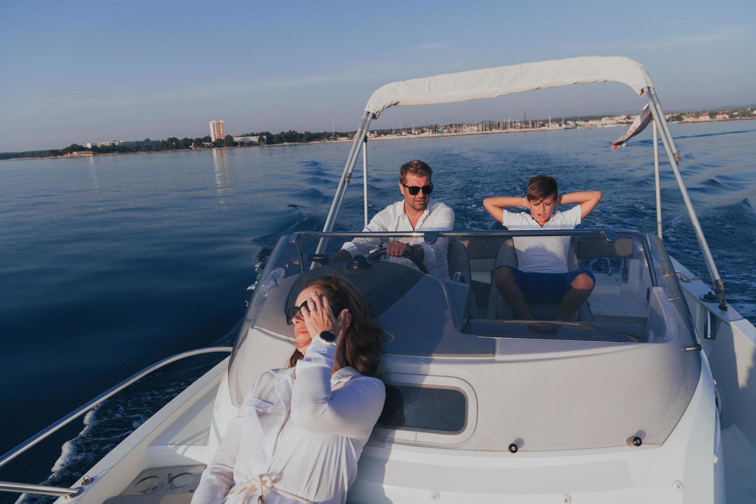 A senior couple in casual outfits with their son enjoy while riding a boat at sea at sunset. The concept of a happy family. Selective focus photo