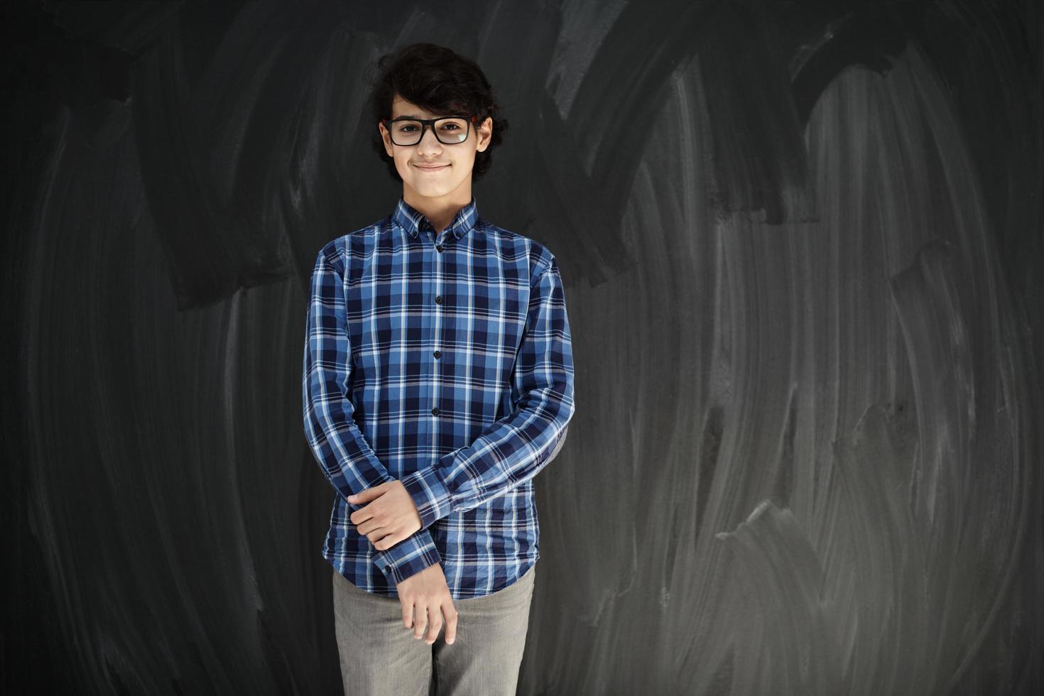 retrato de un adolescente árabe de aspecto inteligente con gafas contra una pizarra negra foto