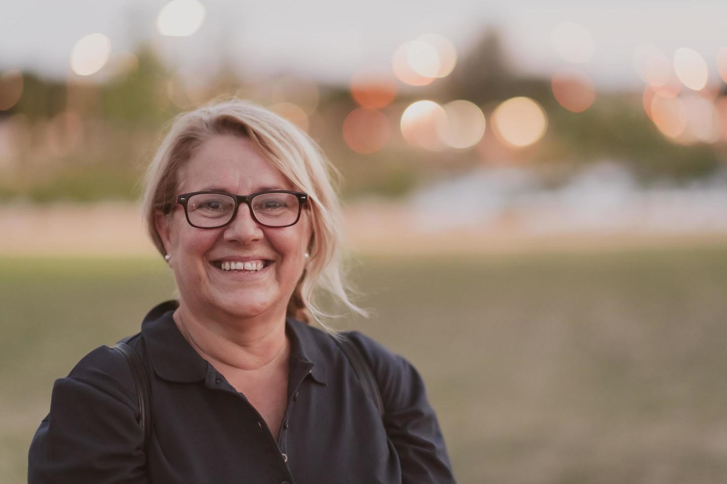 Portrait of an elderly woman with blonde hair and glasses on the beaches of the Mediterranean Sea at sunset. Selective focus photo