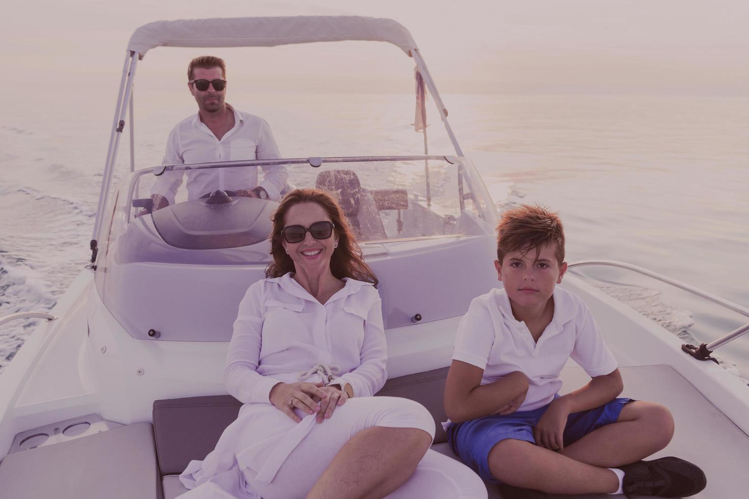 A senior couple in casual outfits with their son enjoy while riding a boat at sea at sunset. The concept of a happy family. Selective focus photo