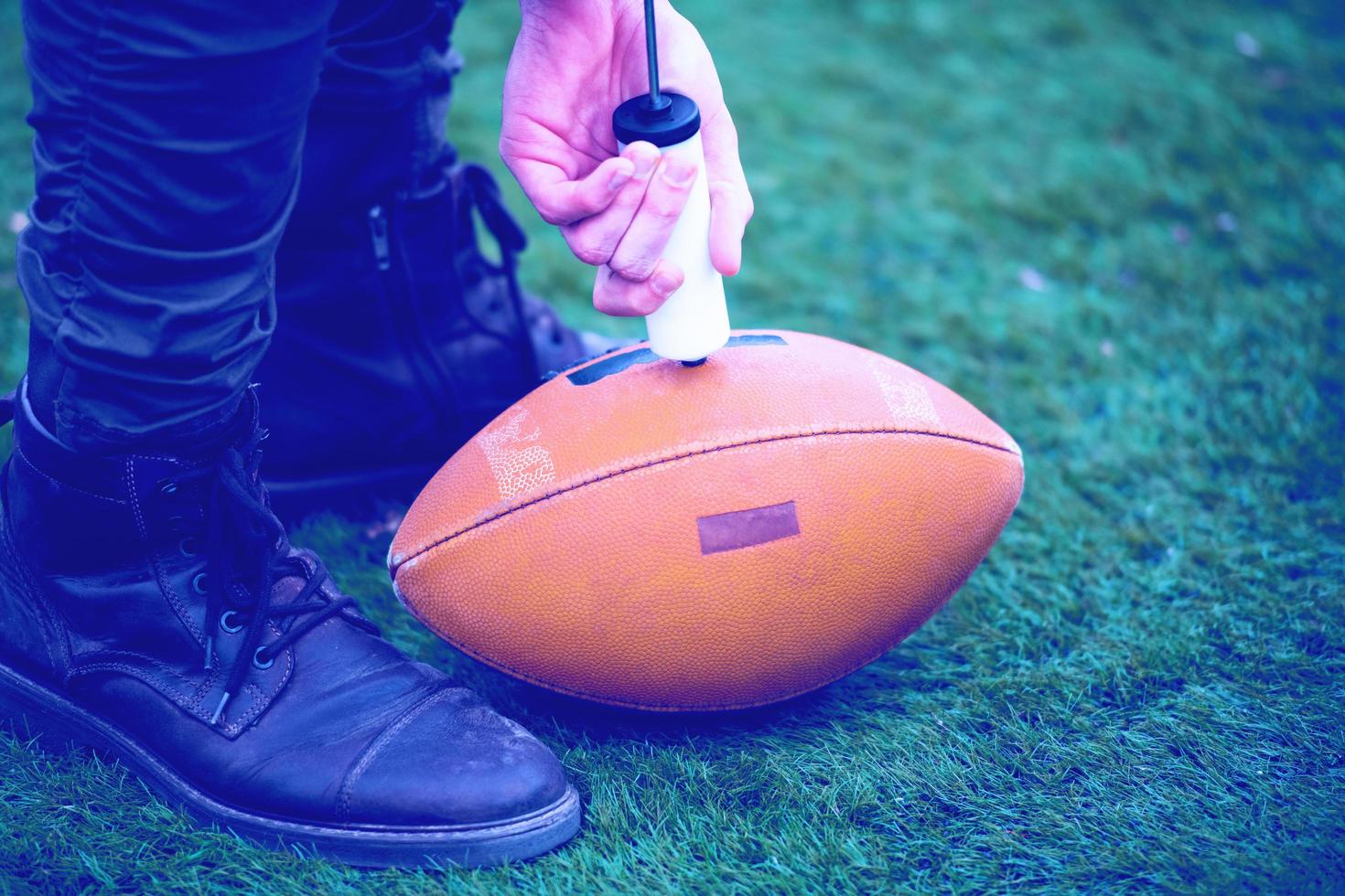 man pumping air into american football ball photo