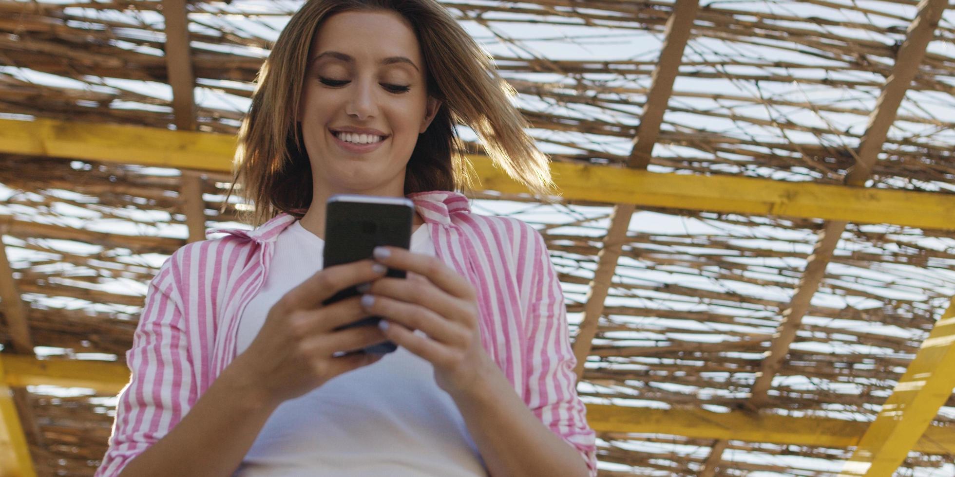 mujer smartphone enviando mensajes de texto por teléfono celular en la playa foto