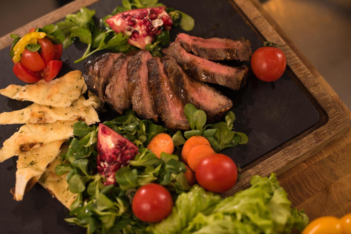 Juicy slices of grilled steak on wooden board photo