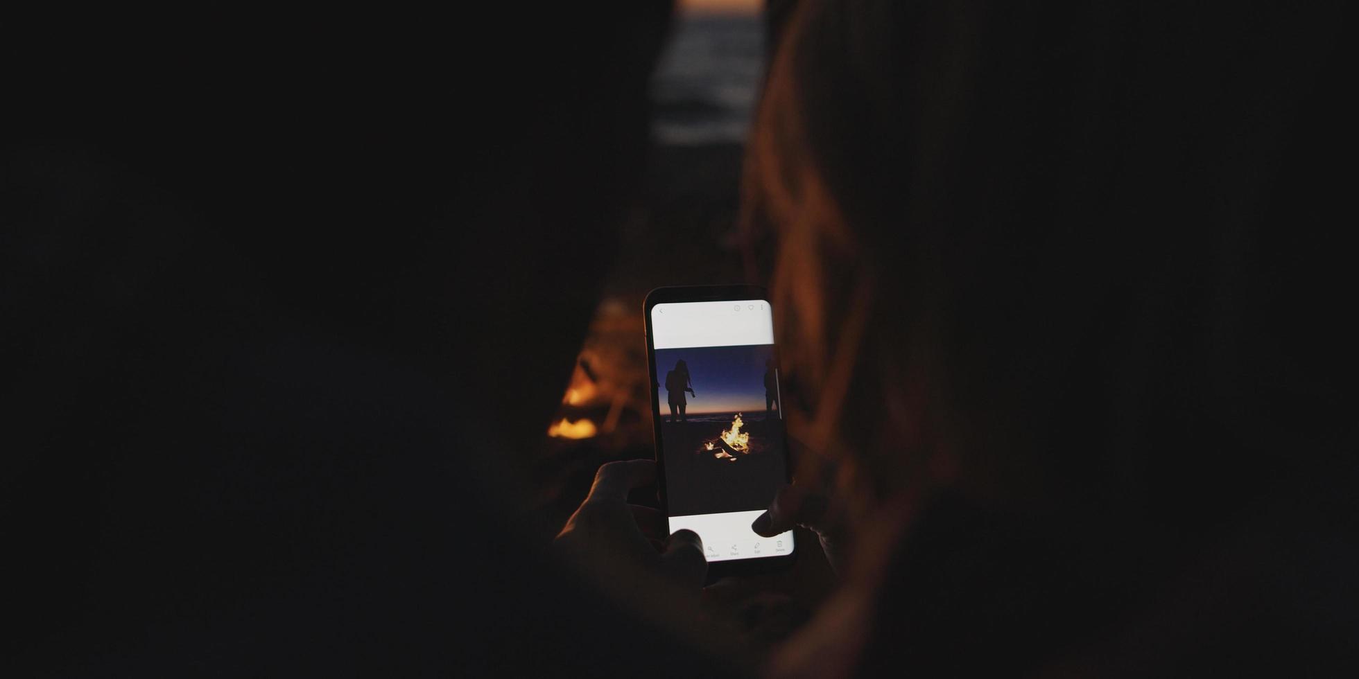 Couple taking photos beside campfire on beach