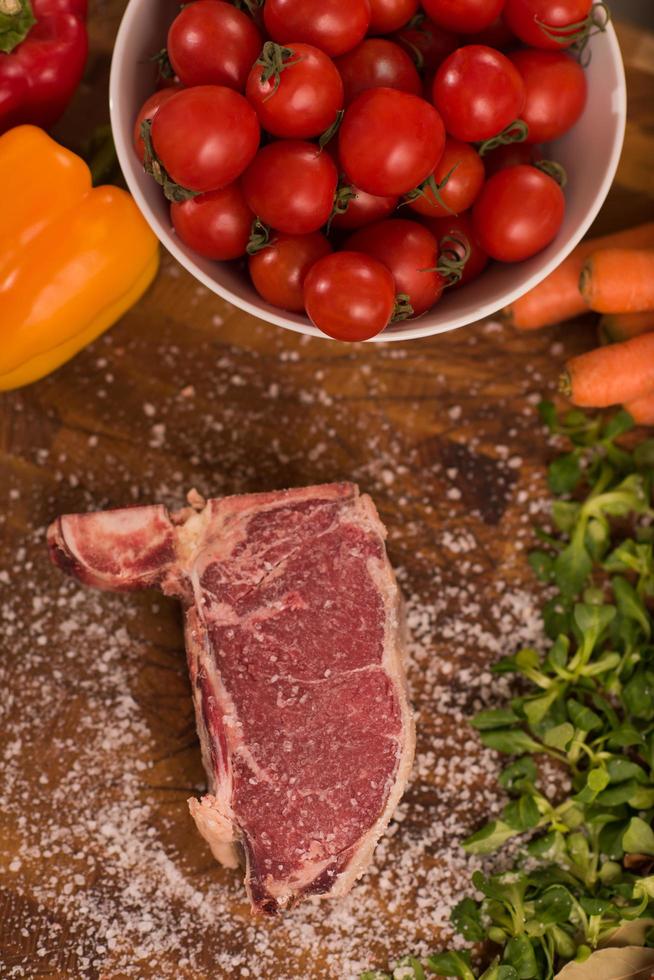 Juicy slice of raw steak on wooden table photo