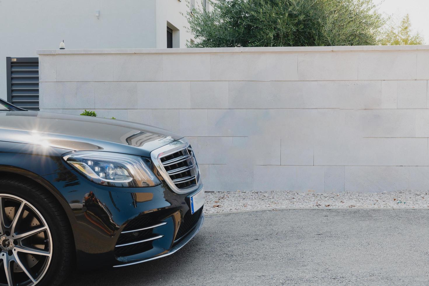 Close up photo of luxury car parked in front of a wall