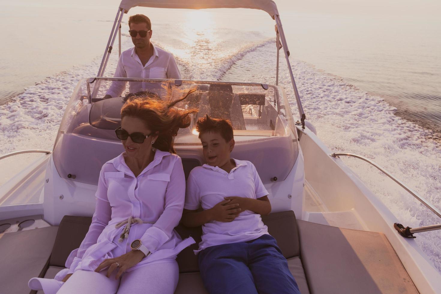 A senior couple in casual outfits with their son enjoy while riding a boat at sea at sunset. The concept of a happy family. Selective focus photo