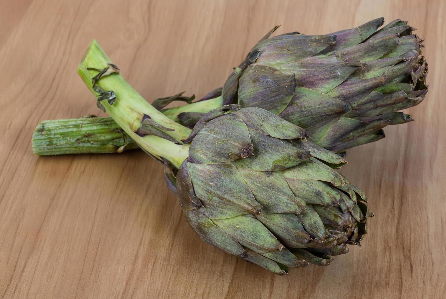 Raw artichokes on wood photo