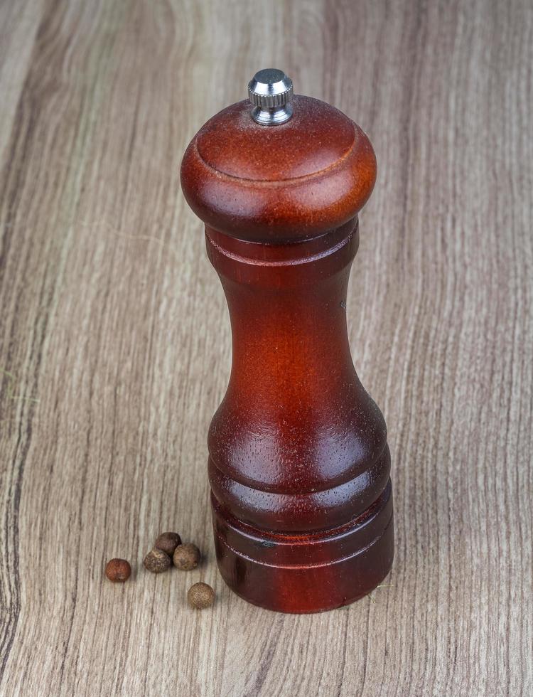 Pepper mill on wooden background photo