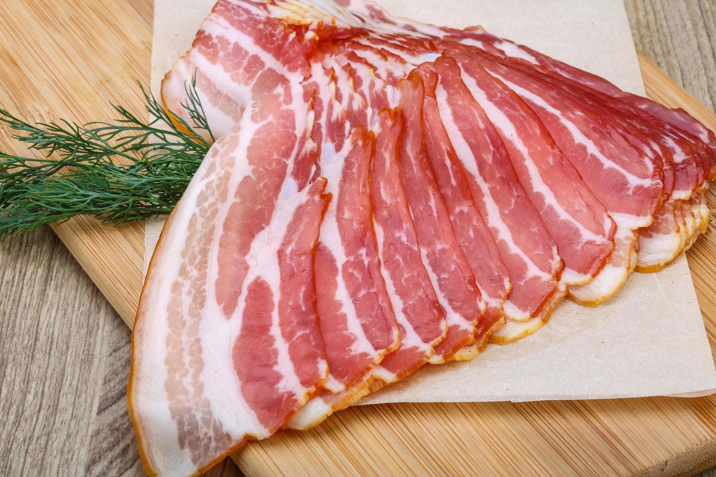 Sliced bacon on wood photo