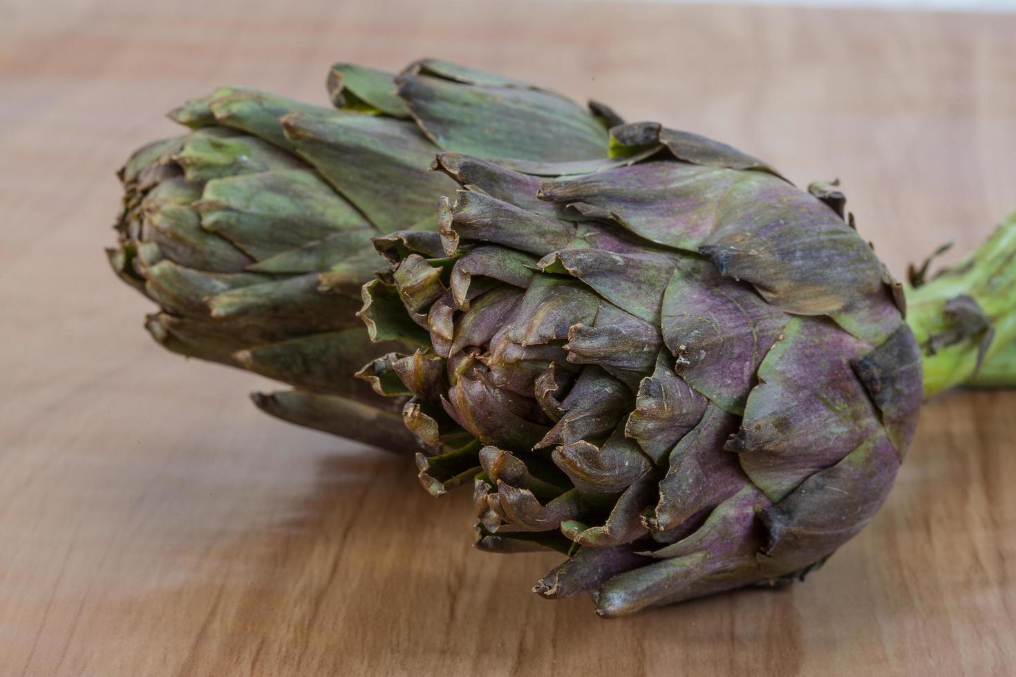 Raw artichokes on wood photo