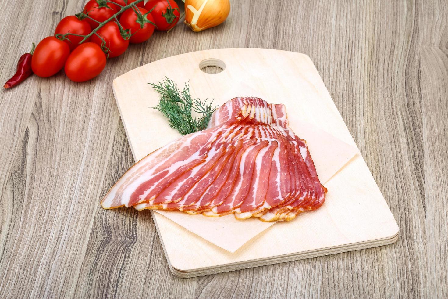 Sliced bacon on wood photo
