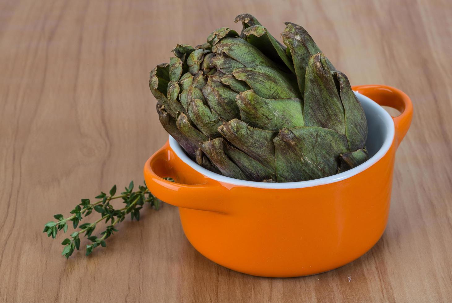 Raw artichokes on wood photo