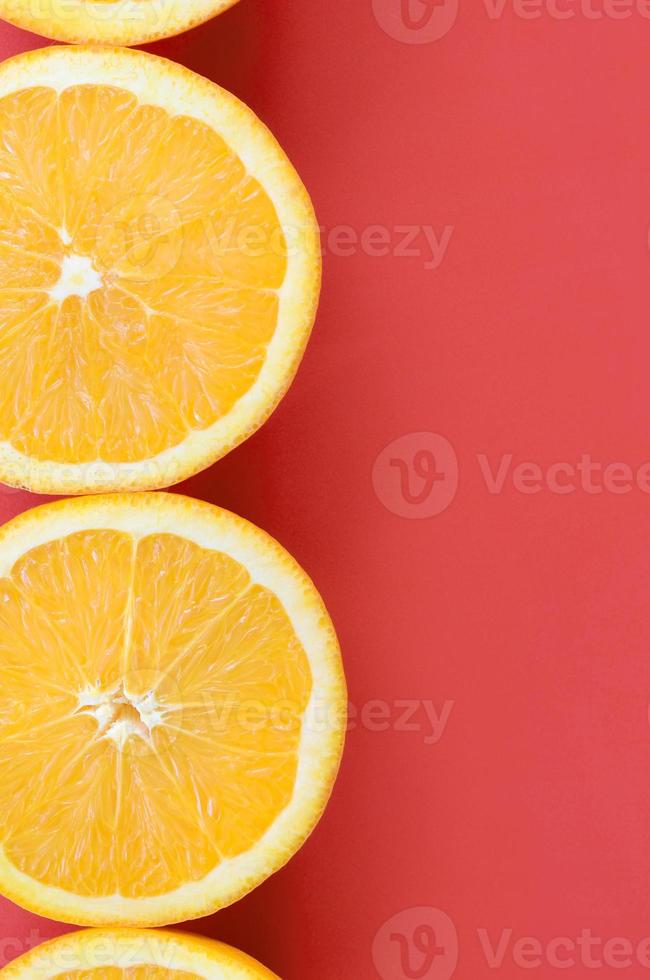 Top view of a several orange fruit slices on bright background in red color. A saturated citrus texture image photo