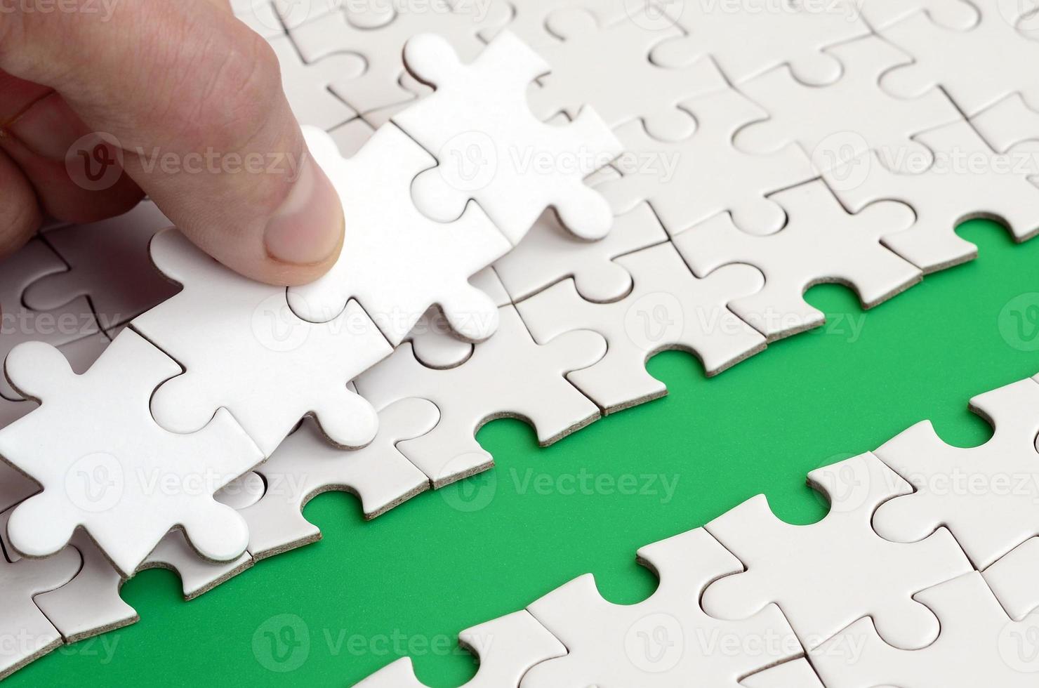 The human hand paves the way to the surface of the jigsaw puzzle, forming a green space. The concept of overcoming the difficulties on the way to success photo