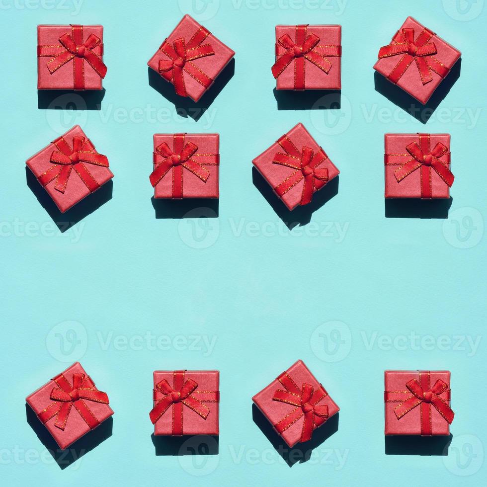 Many small red pink gift boxes on texture background of fashion trendy pastel blue color paper in minimal concept. Abstract pattern photo