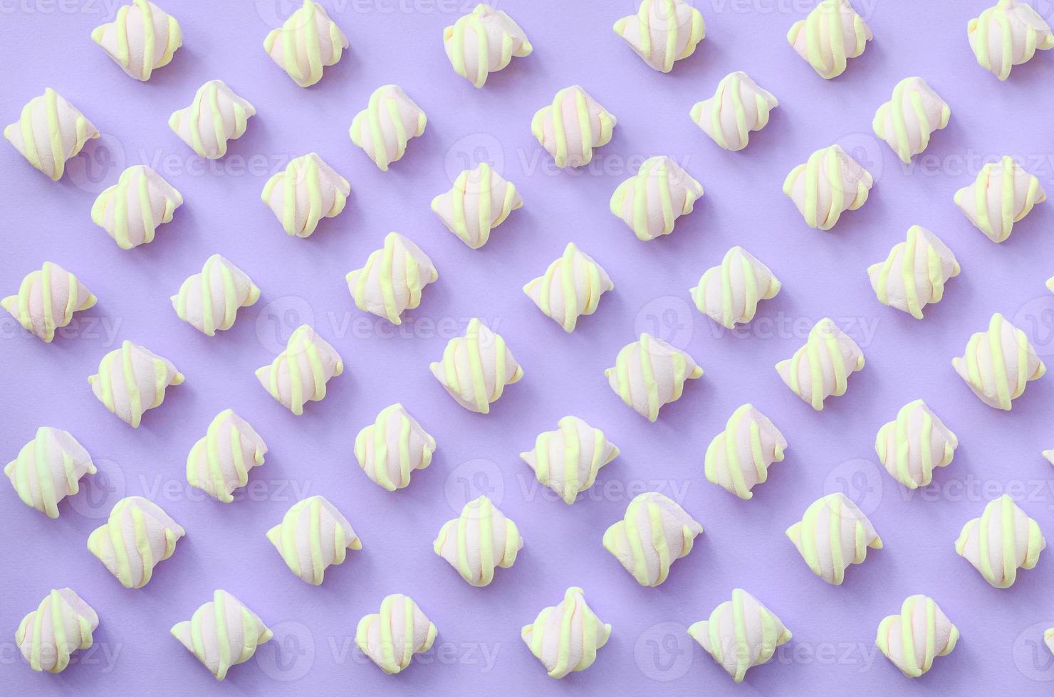 Colorful marshmallow laid out on violet paper background. pastel creative textured pattern. minimal photo