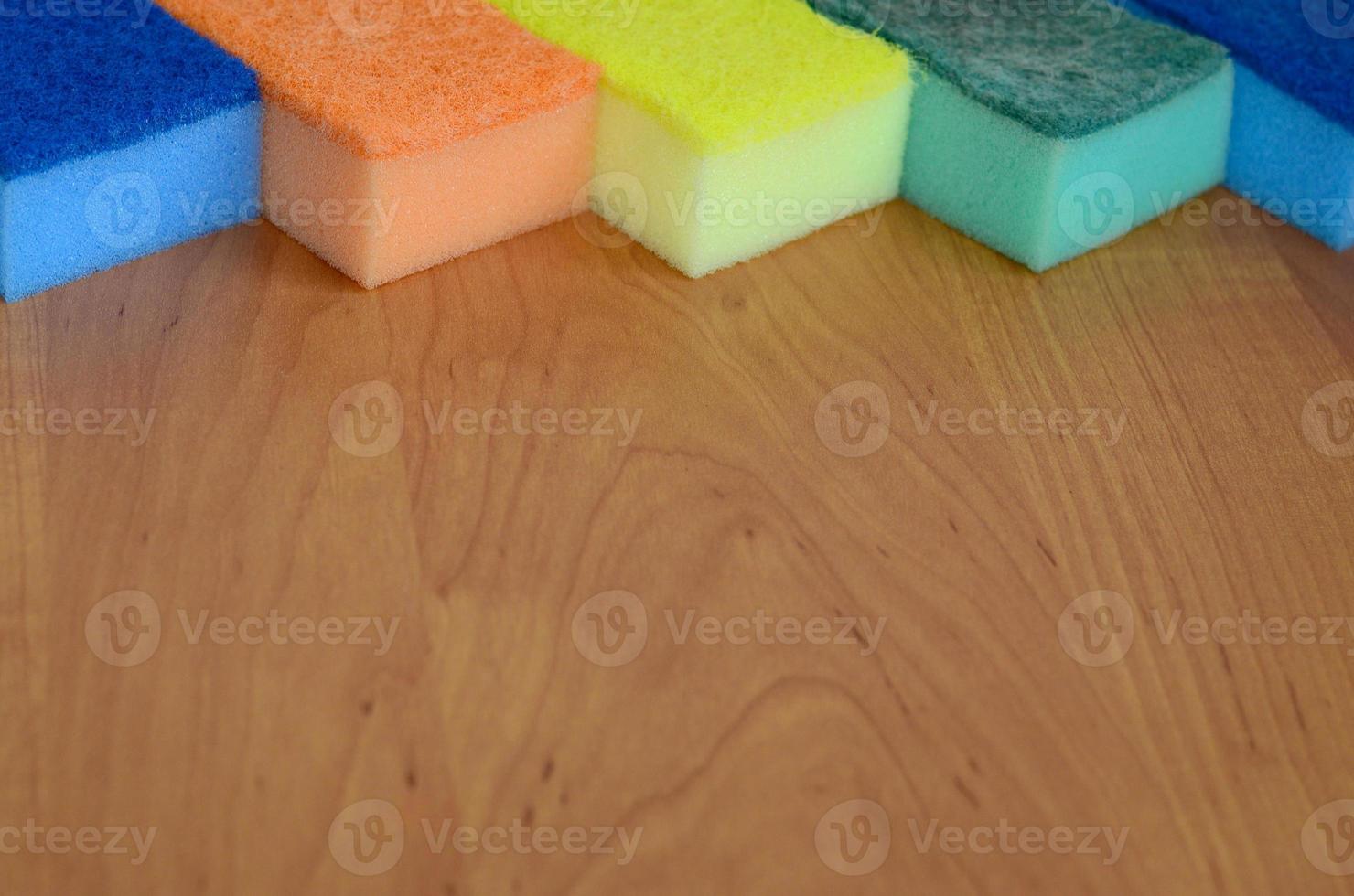 A few kitchen sponges lie on a wooden kitchen countertop. Colorful