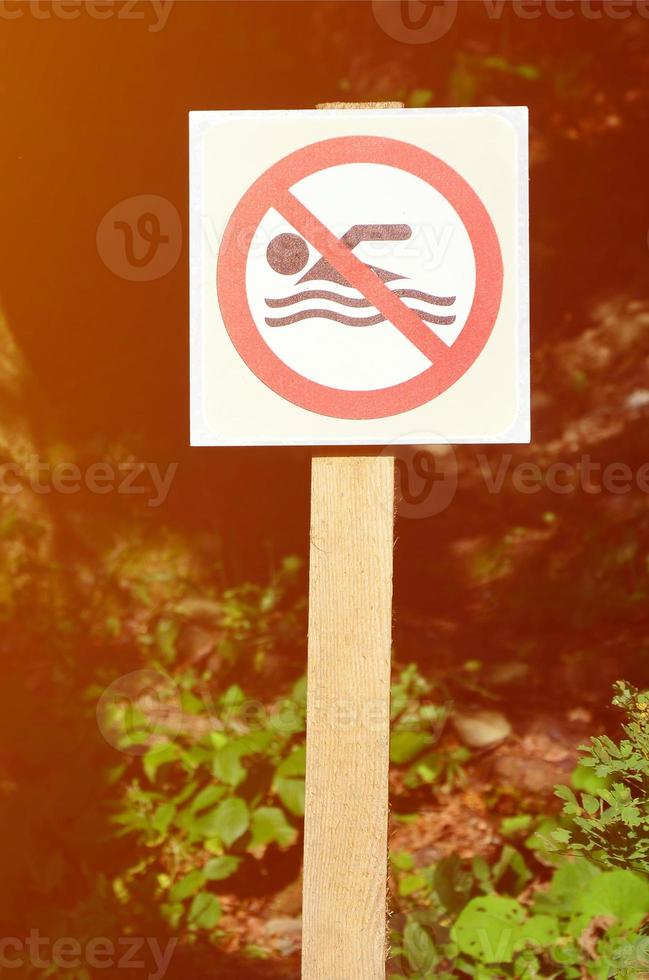 A pillar with a sign denoting a ban on swimming. The sign shows a crossed-out floating person photo