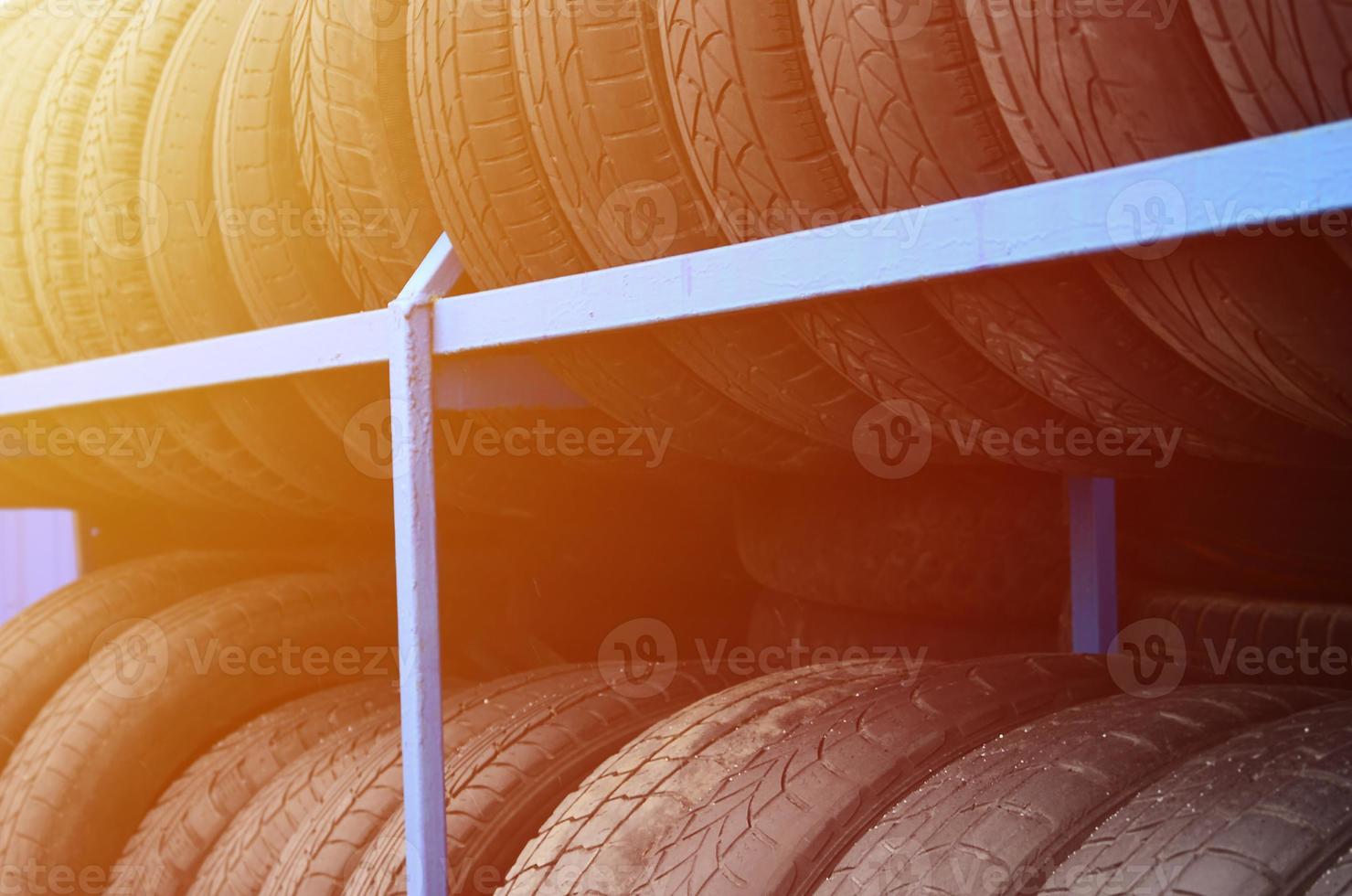 Rack with variety of car tires in automobile store. Many black tires. Tire stack background. Selective focus photo