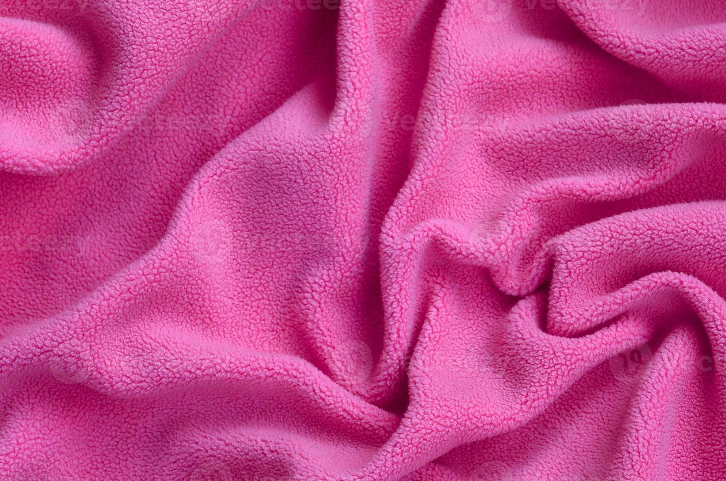 The blanket of furry pink fleece fabric. A background of light pink soft plush fleece material with a lot of relief folds photo