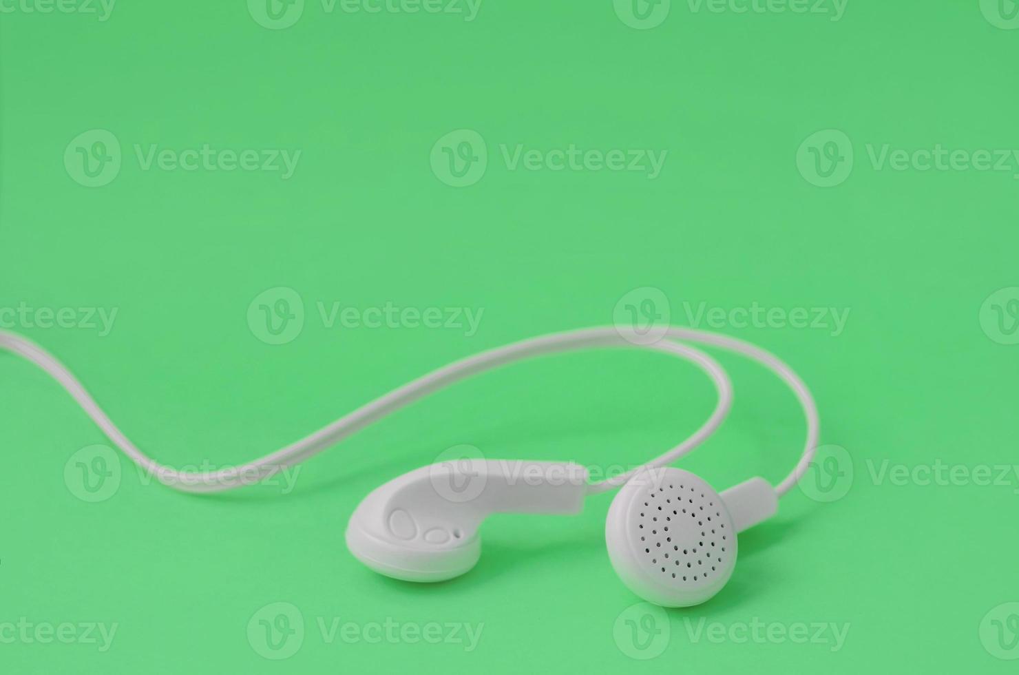 A template for music listening fans. White earphones on green photo