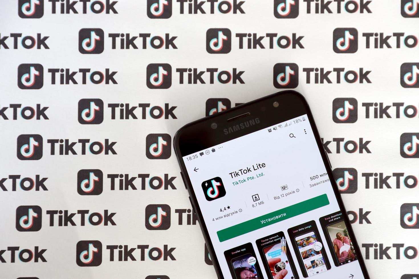 TERNOPIL, UKRAINE - MAY 2, 2022 Tik Tok smartphone app on screen and Many TikTok logo printed on paper. Tiktok or Douyin is a famous Chinese short-form video hosting service owned by ByteDance photo