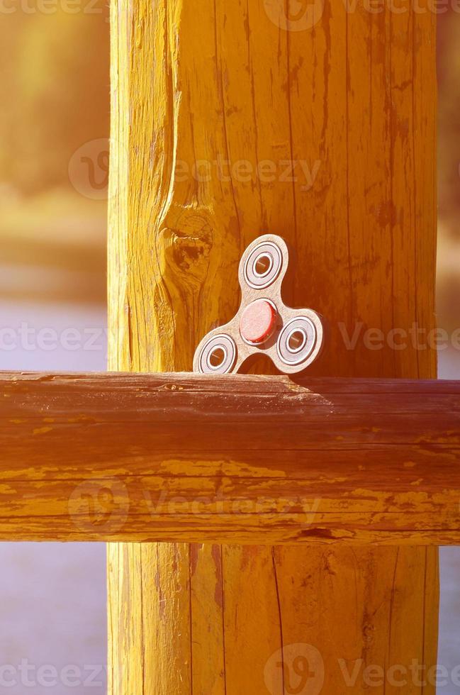 A wooden spinner lies on a wooden bar against a background of river water photo