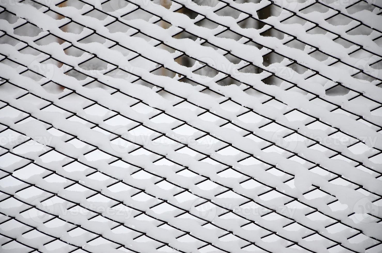 Close-up metal mesh covered with a thick layer of snow in the cells photo