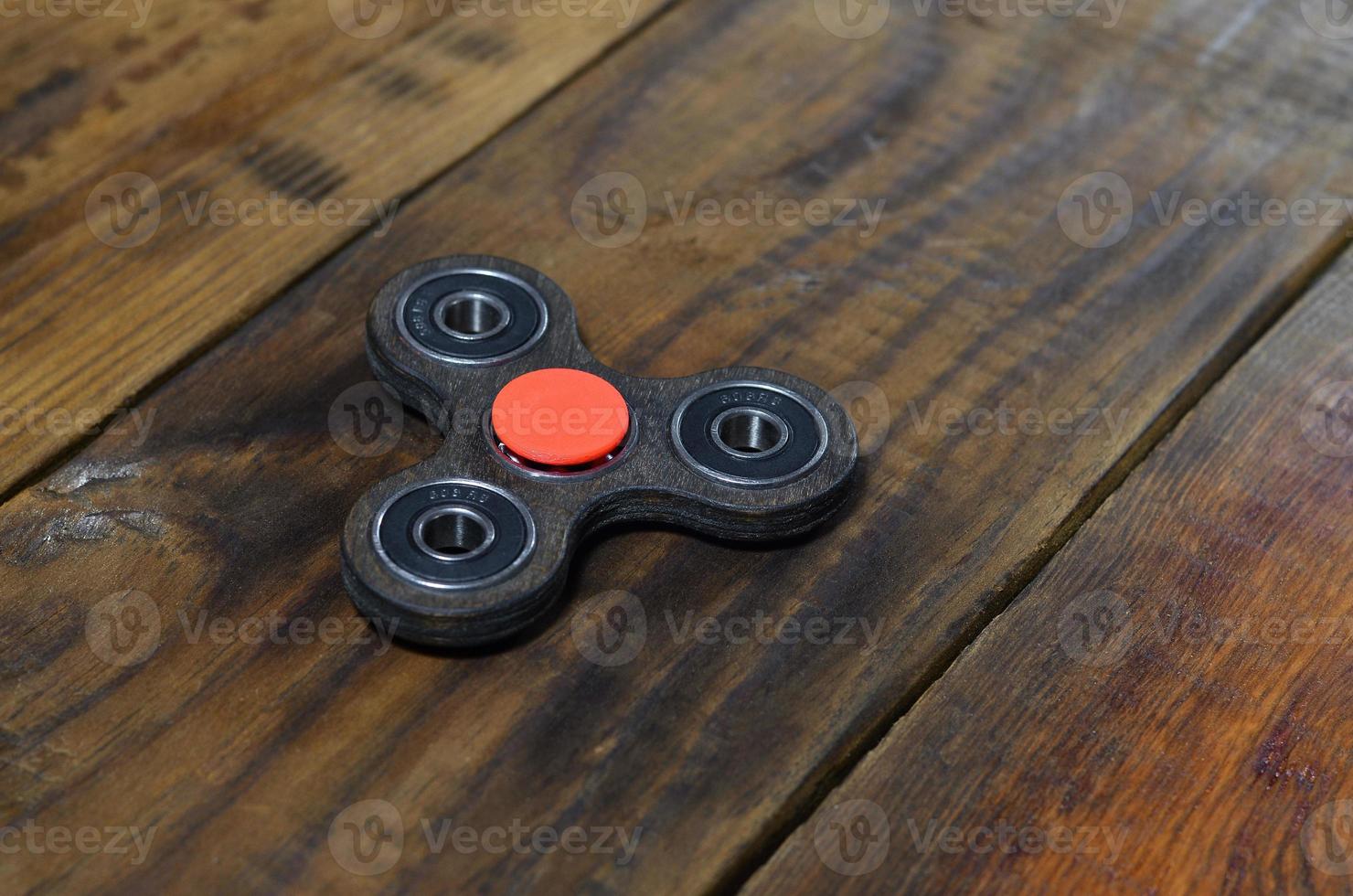A rare handmade wooden fidget spinner lies on a brown wooden background surface. Trendy stress relieving toy photo