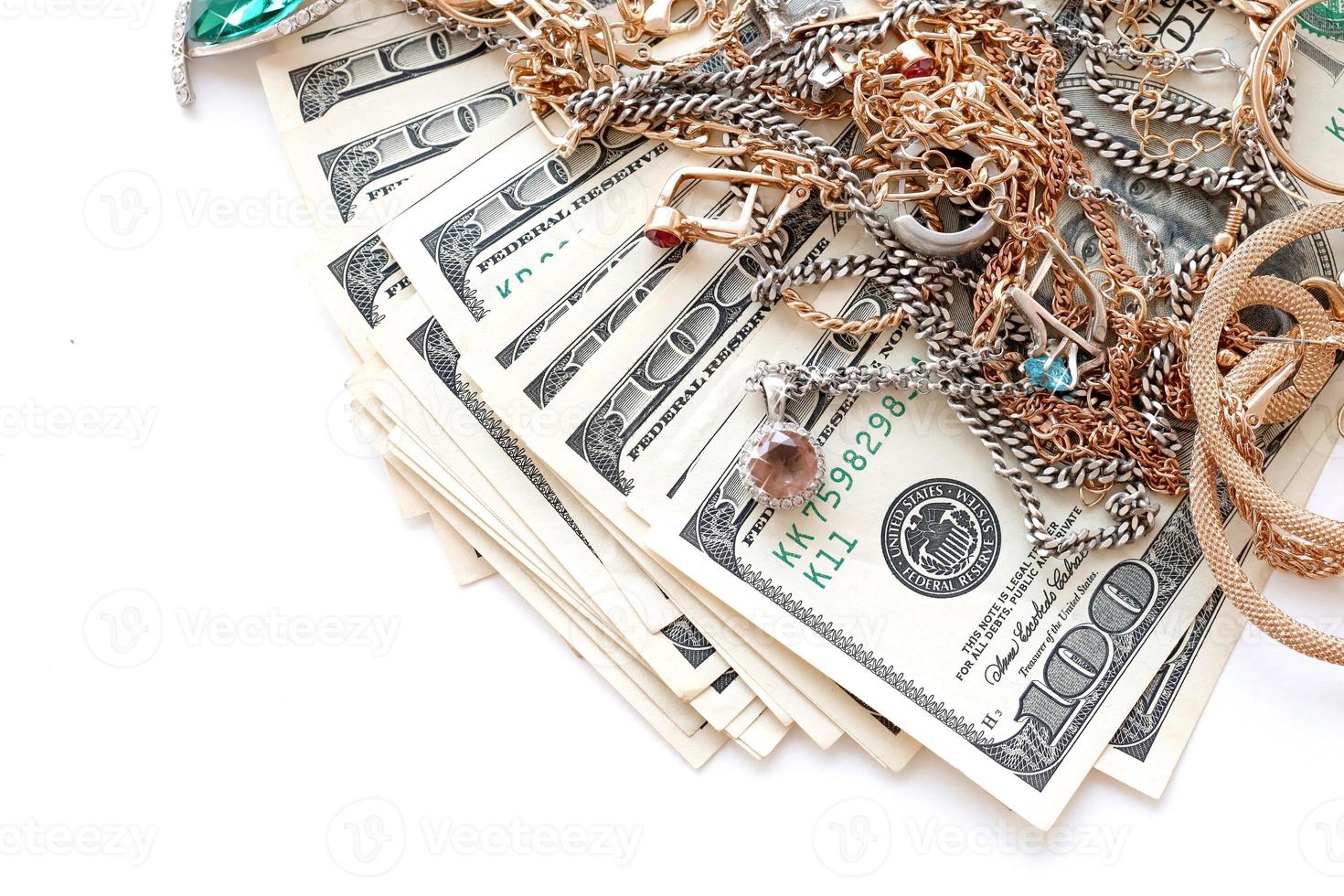 Many expensive golden and silver jewerly rings, earrings and necklaces with big amount of US dollar bills on white background. Pawnshop or jewerly shop photo