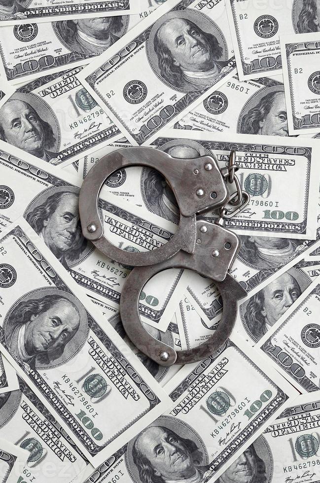 Police handcuffs lie on a lot of dollar bills. The concept of illegal possession of money, illegal transactions with US dollars. Economic Crime photo