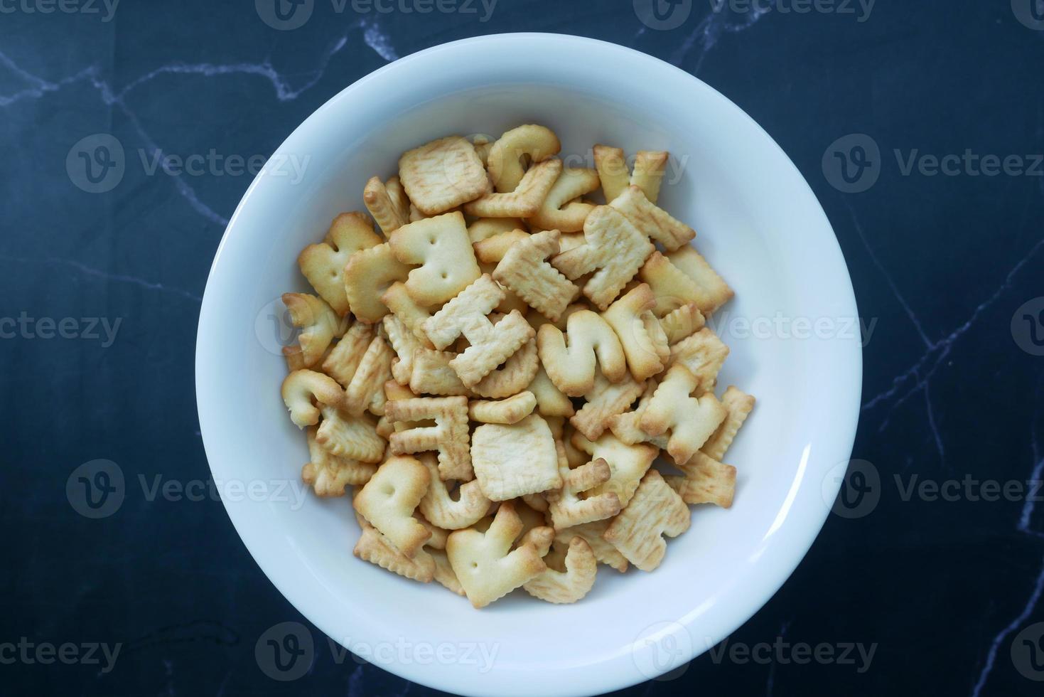 letter shape sweet cookies in a white bowl on black photo