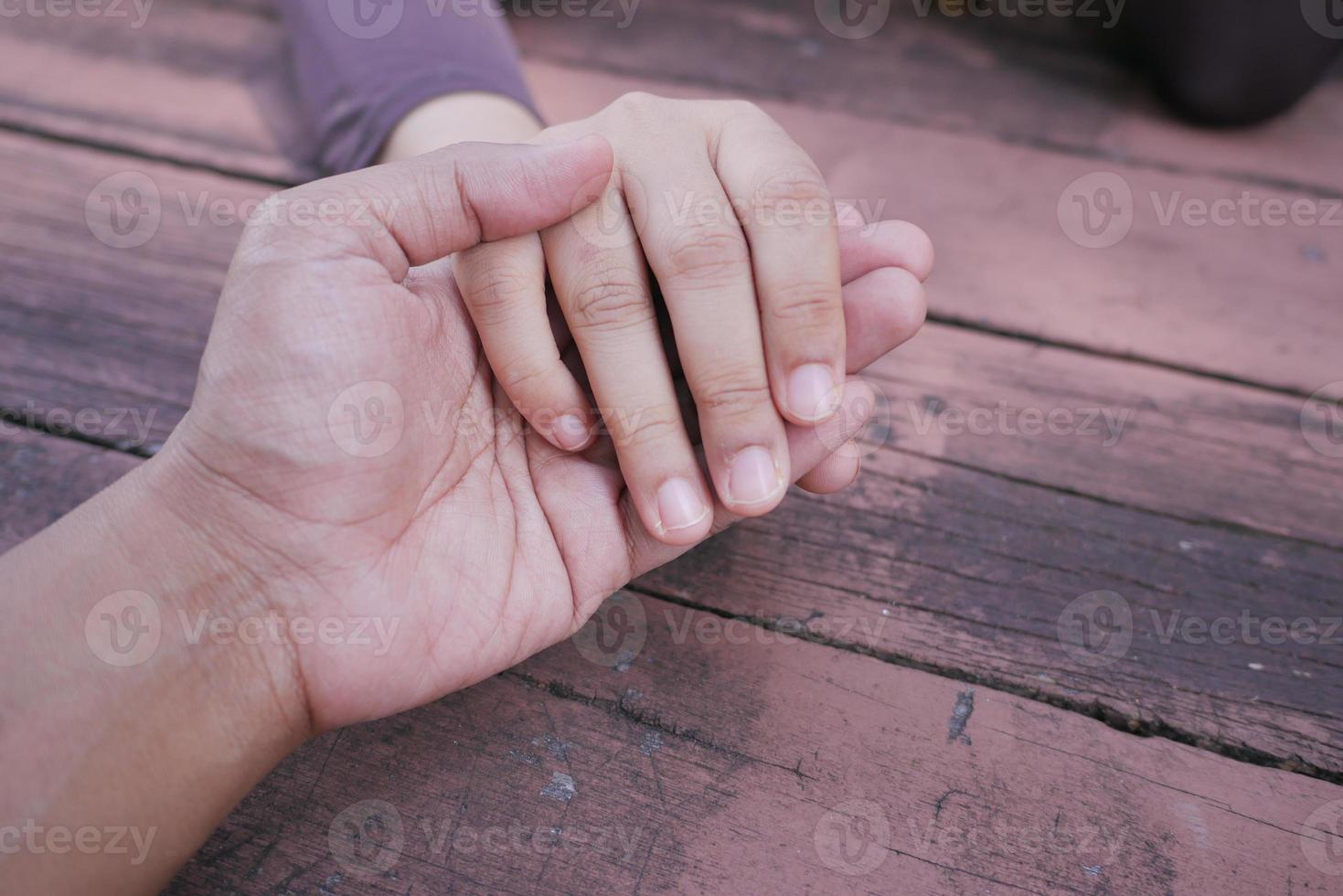 Close up of couple holding hands against orange background. photo