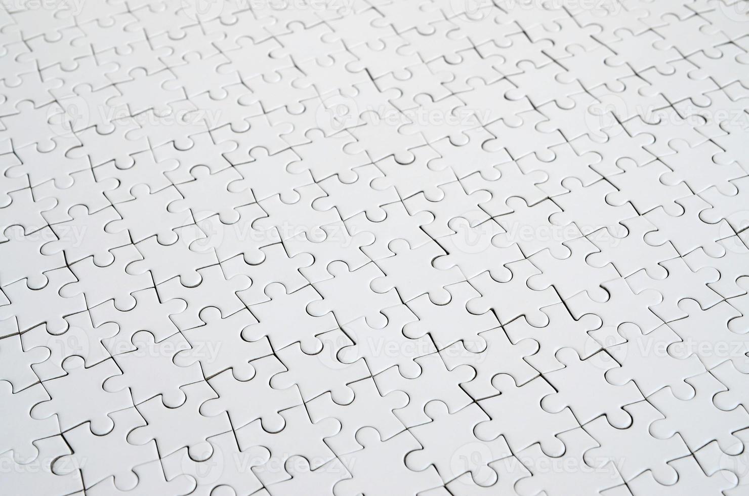 Close up of a white jigsaw puzzle in assembled state in perspective. Many components of a large whole mosaic are united photo