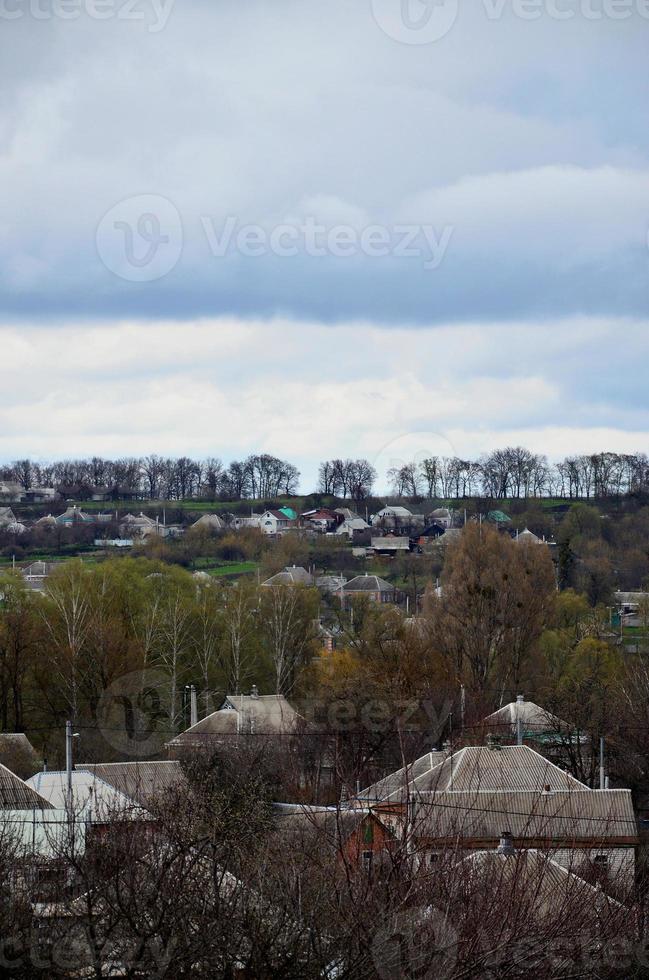 un paisaje rural con muchas casas privadas y árboles verdes. panorama suburbano en una tarde nublada. un lugar lejos de la ciudad foto